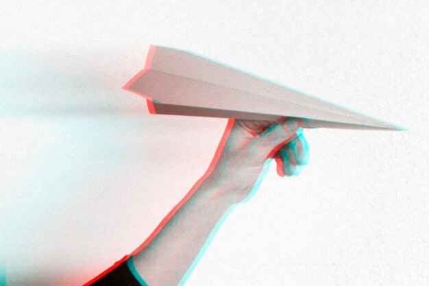 Efekt anaglifu na dłoni trzymającej papierowy samolot
