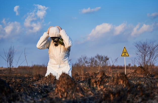 Ekolog stojący na kolanach w polu ze spaloną trawą