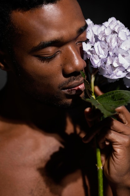 Ekspresyjny mężczyzna pozuje z kwiatem z bliska