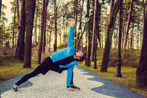 Bezpłatne zdjęcie elastyczny mężczyzna fitness w niebieskiej kurtce sportowej, ćwiczenia na zewnątrz.