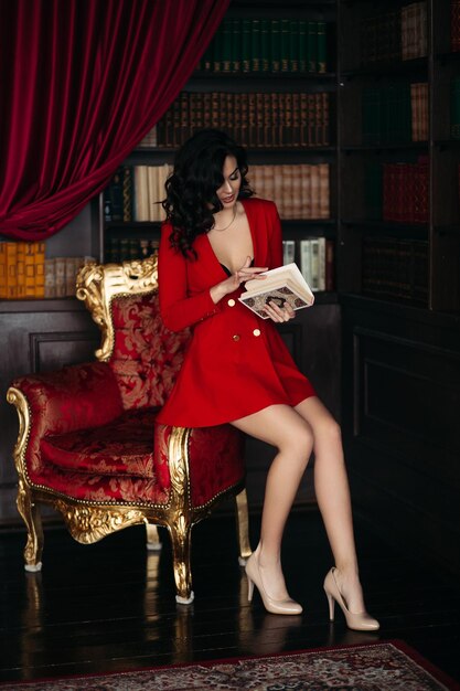Elegancka brunetka w czerwieni siedzi i trzyma książkę