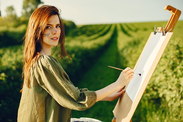 Elegancka i piękna dziewczyna maluje w polu
