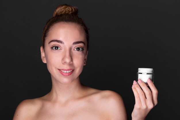 Bezpłatne zdjęcie elegancka kobieta trzyma produkt do pielęgnacji skóry