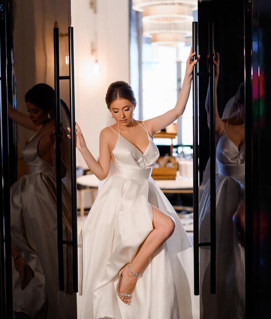 Elegancka narzeczona w sukni ślubnej pozuje między drzwiami