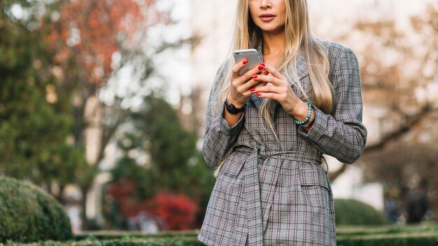 Elegancki bizneswoman patrzeje smartphone w mieście