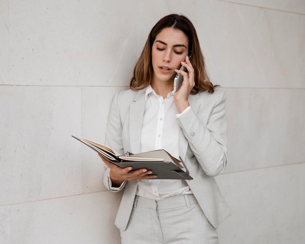 Bezpłatne zdjęcie elegancki bizneswoman rozmawia przez telefon z porządkiem obrad