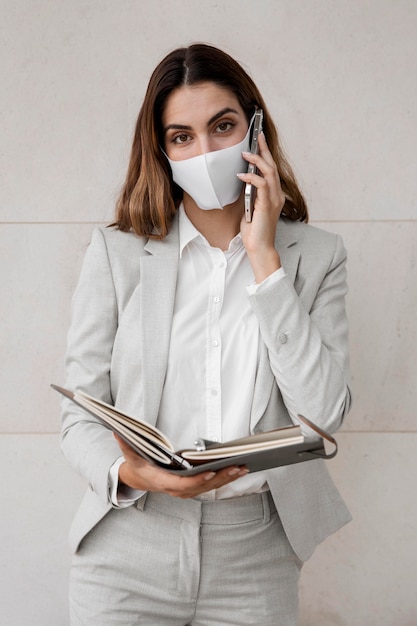 Elegancki bizneswoman z maską rozmawia przez telefon