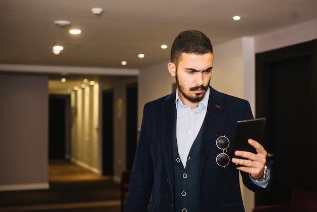 Bezpłatne zdjęcie elegancki człowiek za pomocą tabletu w hali