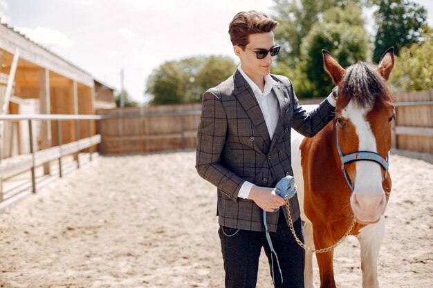 Elegancki mężczyzna stojący obok konia na ranczo