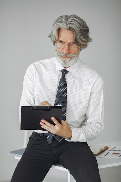 Elegancki mężczyzna w biurze. Biznesmen w białej koszuli. Mężczyzna pracuje z dokumentami.