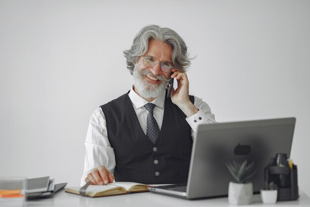 Elegancki mężczyzna w biurze. Biznesmen w białej koszuli. Mężczyzna pracuje z telefonem.