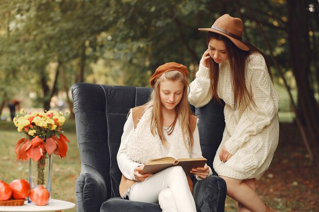 Eleganckie i stylowe dziewczyny siedzą na krześle w parku