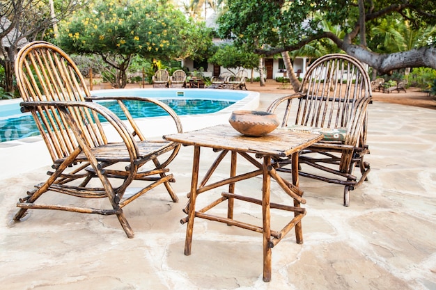 Eleganckie krzesła wykonane z drewna w pobliżu basenu w kenijskim ogrodzie
