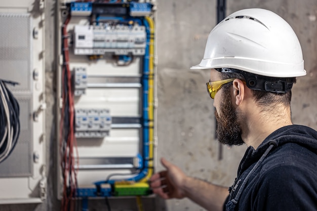 Bezpłatne zdjęcie elektryk mężczyzna pracuje w rozdzielnicy z elektrycznym kablem połączeniowym