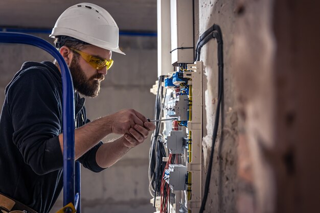 Elektryk mężczyzna pracuje w rozdzielnicy z elektrycznym kablem połączeniowym