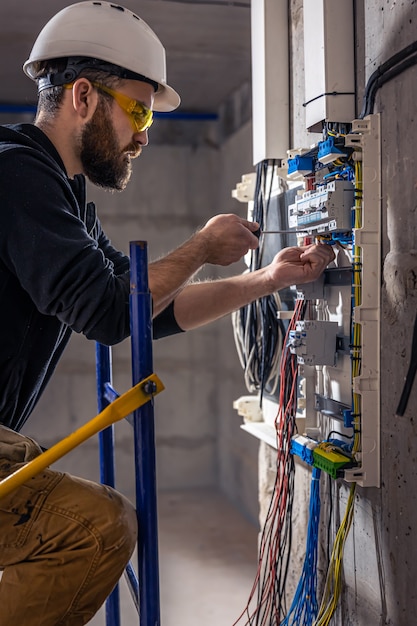 Elektryk mężczyzna pracuje w rozdzielnicy z elektrycznym kablem połączeniowym