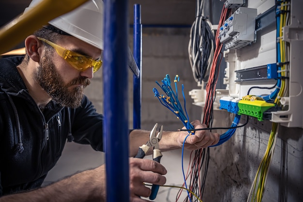 Elektryk mężczyzna pracuje w rozdzielnicy z elektrycznym kablem połączeniowym