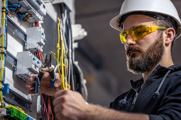 Elektryk mężczyzna pracuje w rozdzielnicy z elektrycznym kablem połączeniowym.