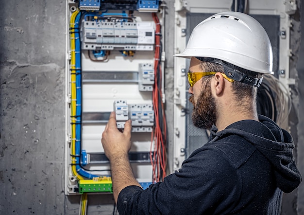 Elektryk mężczyzna pracuje w rozdzielnicy z elektrycznym kablem połączeniowym.