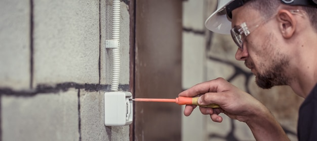 Bezpłatne zdjęcie elektryk-technik, łączy sprzęt za pomocą narzędzia