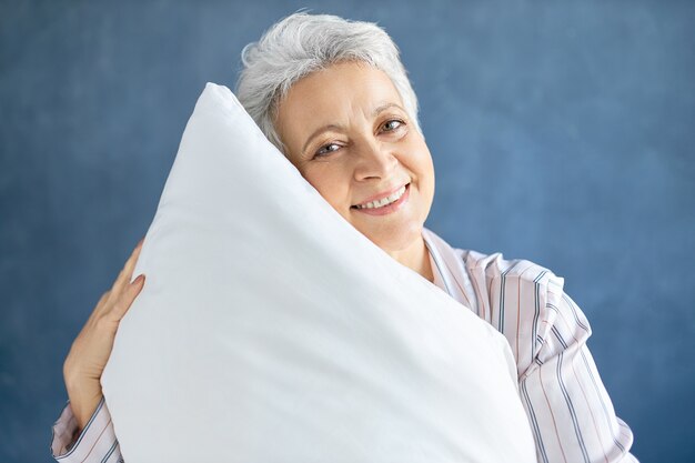 Emerytka pozowanie i przytulanie białej miękkiej poduszki