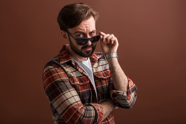 Emocjonalne hipster przystojny stylowy brodaty mężczyzna z zabawnym wyrazem twarzy na brązowym