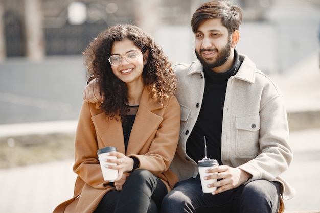 European girl anindian guy jeździć na skuterach i uśmiechać się. Ludzie z kawą.