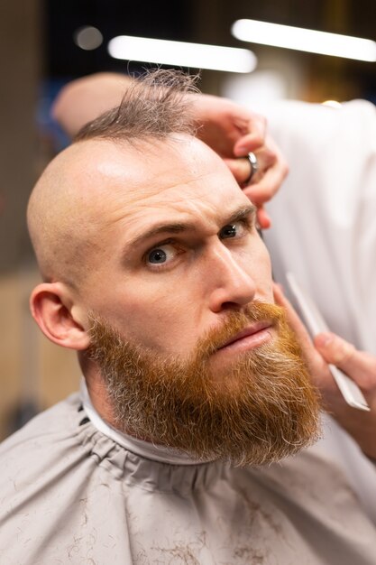 Europejski brutalny mężczyzna z obciętą brodą w zakładzie fryzjerskim