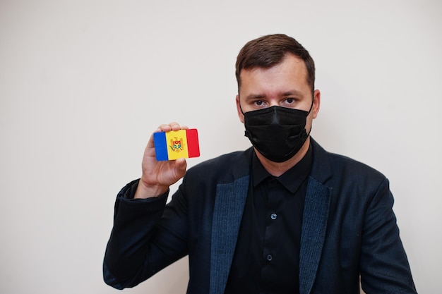 Europejski mężczyzna nosi czarną maskę formalną i chroni twarz trzymaj flagę Mołdawii na białym tle Europa koronawirus Covid koncepcja kraju