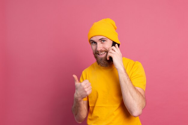 Europejski przystojny szczęśliwy wesoły mężczyzna rozmawia na smartfonie uśmiechając się na różowo