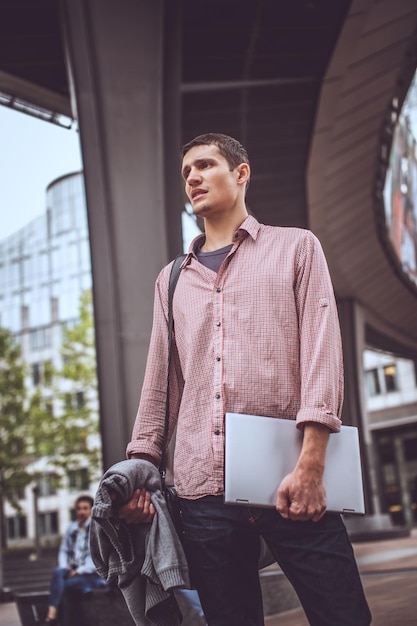 Facet na nowoczesnej ulicy w swobodnym ubraniu z laptopem