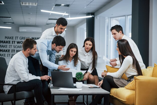 Facet pokazuje dokument dziewczynie. Grupa młodych freelancerów w biurze ma rozmowę i pracę