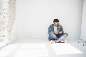 Bezpłatne zdjęcie facet w zwykłym ubraniu siedzi w domu w pustym mieszkaniu z kartą kredytową