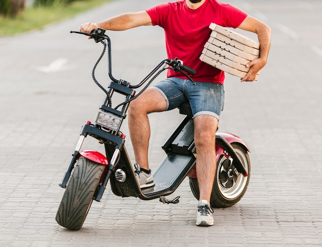 Bezpłatne zdjęcie facet z bliska dostawy na motocyklu z pizzy