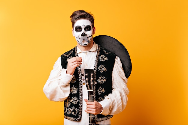 Bezpłatne zdjęcie facet z makijażem na halloween i sombrero za plecami bawi się i pozuje z fałszywymi wąsami.