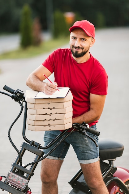 Bezpłatne zdjęcie facet ze średnim strzałem z motocyklem i pizzą