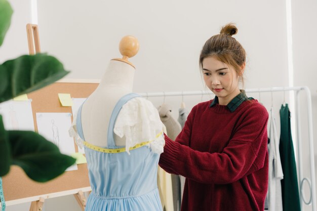 Fachowy piękny Azjatycki żeński projektant mody pracuje pomiarową suknię na mannequin odzieży