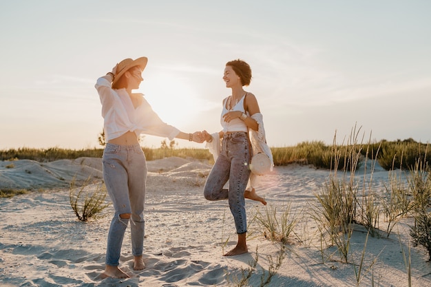 Fajne dwie młode kobiety bawiące się na plaży o zachodzie słońca, gejowskie lesbijki kochają romans