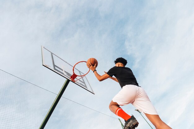 Fajny sportowy człowiek rzucający koszykówkę w obręcz