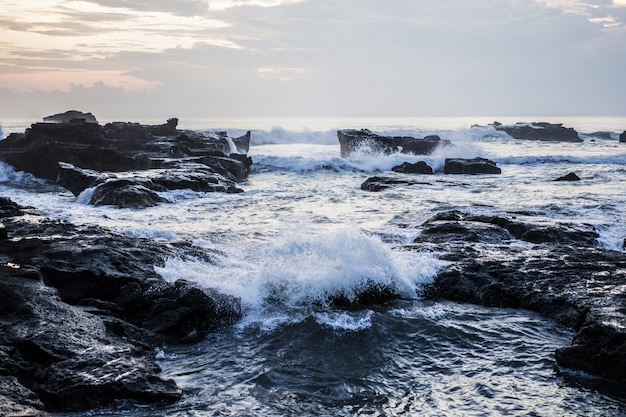 Bezpłatne zdjęcie fale oceanu pękają na skałach. rozpryskiwania fal oceanu o zachodzie słońca.