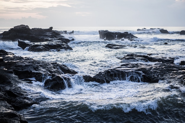 fale oceanu pękają na skałach. rozpryskiwania fal oceanu o zachodzie słońca.