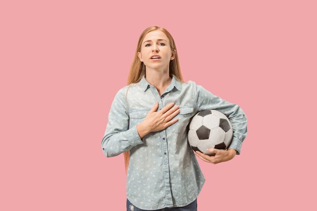 Fan sport kobieta gracz trzymając piłkę nożną na białym tle na tle różowego studia