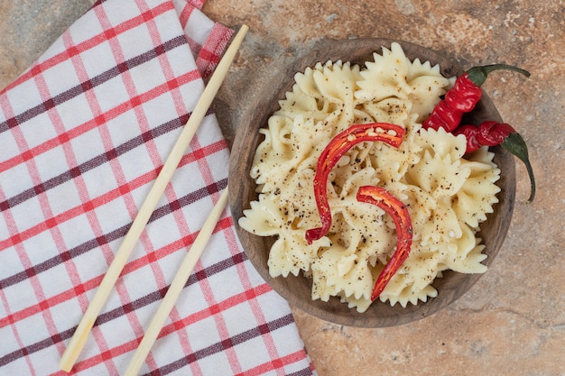 Bezpłatne zdjęcie farfalle z papryczką chili i przyprawami w drewnianej misce. wysokiej jakości ilustracja