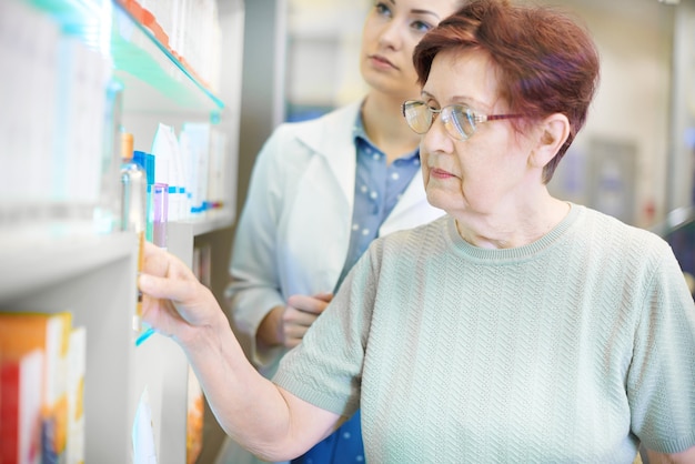 Farmaceuta pomaga starszej kobiecie z receptą