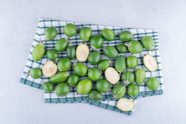 Bezpłatne zdjęcie feijoas na złożonym obrusie na marmurowym tle.