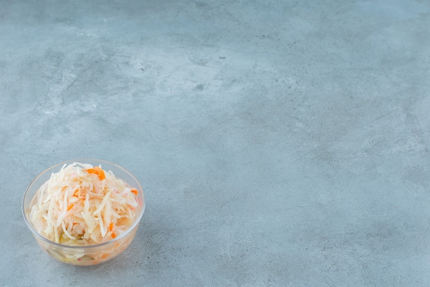 Bezpłatne zdjęcie fermentowana kapusta kiszona z marchewką w misce na niebieskim stole.