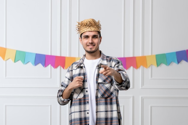 Festa junina przystojny facet w kraciastej koszuli w słomkowym kapeluszu świętuje festiwal wskazując na kogoś