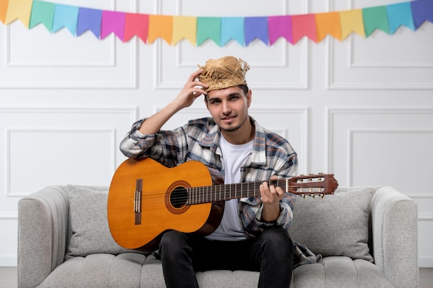 Festa junina uroczy uroczy facet w kraciastej koszuli w słomkowym kapeluszu świętujący festiwal grający na gitarze