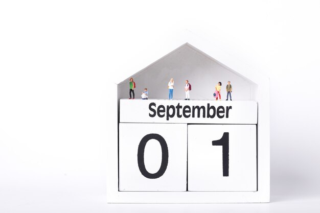 Figurki uczniów stojących na kalendarzu przedstawiającym pierwszy września