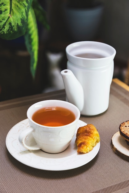 Filiżanka herbaty z czajnikiem i elementami śniadaniowymi